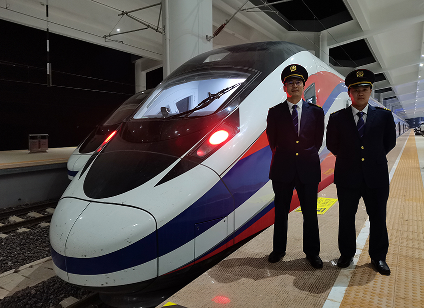 劉銀能（右一）與中國師父鄔俊鴻在動車組前合影。受訪者供圖